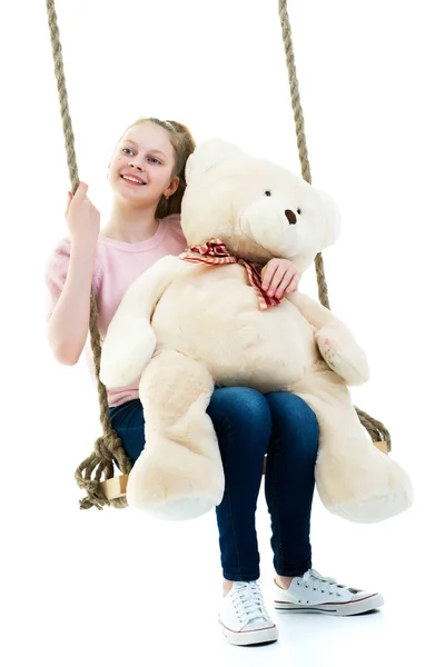 Ένα κοριτσάκι αιωρείται σε μια κούνια με ένα αρκουδάκι. — Φωτογραφία Αρχείου