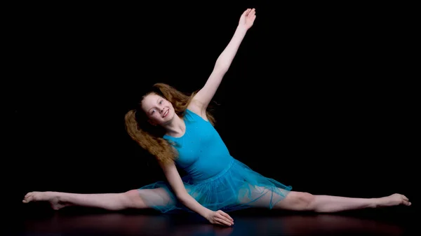 Meisje turner in de studio op een zwarte achtergrond voert gymnastiek — Stockfoto