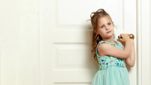 Une petite fille se tient près de la porte . — Photo