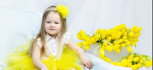 Ein kleines Mädchen mit einem Strauß gelber Tulpen. — Stockfoto