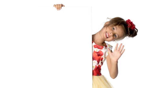 Een klein meisje kijkt van achter een leeg spandoek. — Stockfoto