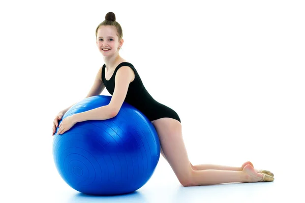 Klein meisje doet oefeningen op een grote bal voor fitness. — Stockfoto