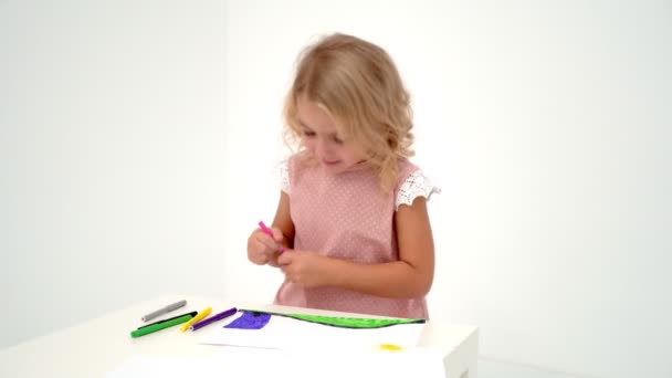 Ein kleines Mädchen zeichnet am Tisch. — Stockvideo