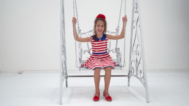 Happy little girl schoolgirl swinging on a swing. — Stock Video