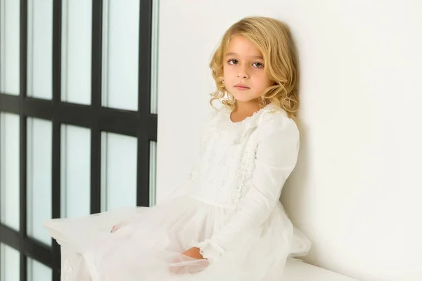 Little girl near a large panoramic window in a large studio.
