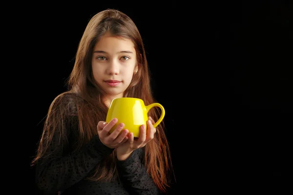 Petite fille avec une tasse sur un fond noir . — Photo