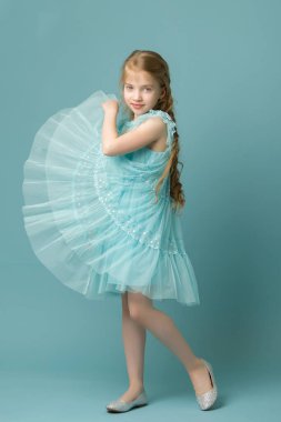 Küçük bir kız ellerini eteğin kenarlarında tutuyor..