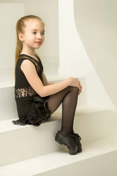 Petite fille dans un costume de danse est assis sur les escaliers. — Photo