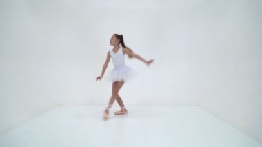 Pompalı ayakkabılı sevimli küçük kız stüdyoda dans ediyor. Beyaz arkaplan üzerinde izole edilmiş.