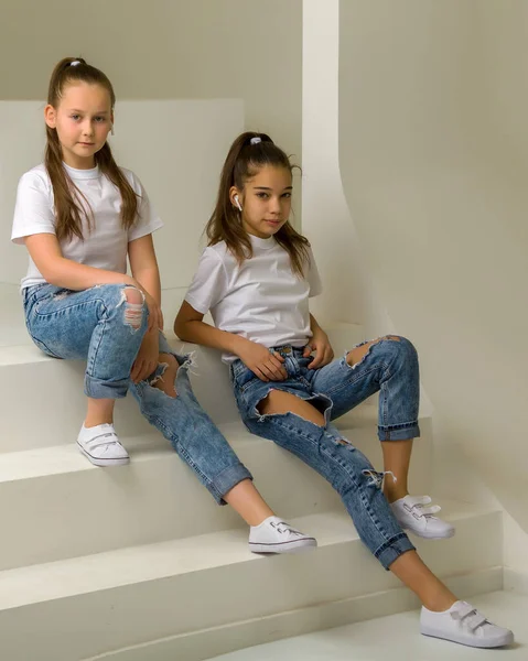 Hermosas niñas están sentadas en las escaleras blancas . —  Fotos de Stock
