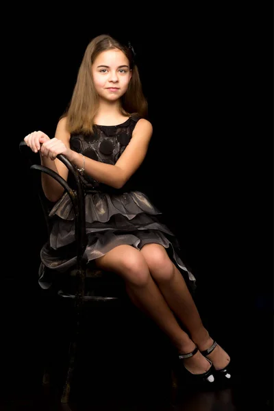 Retrato de una niña sentada en una vieja silla vienesa, blac . — Foto de Stock