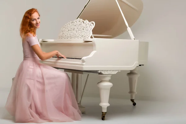 Mulher bonita perto de um piano de cauda branco . — Fotografia de Stock