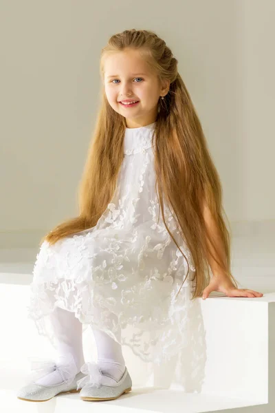 Aranyos kislány ül a stúdióban a fehér lépcsőn.. — Stock Fotó