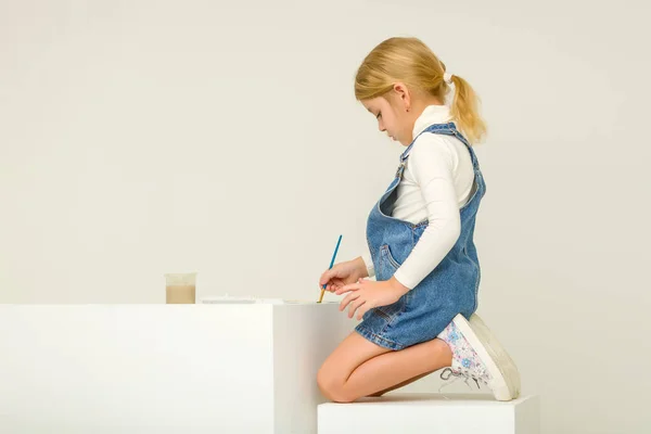 Cute Blonde Girl Sitting on Her Knees and Painting with Brush — Stock Photo, Image