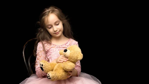 Little girl with a teddy bear on a black background. — Stock Photo, Image