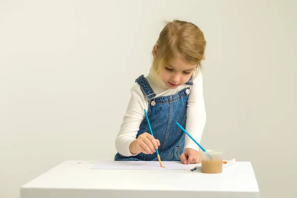 Cute Blonde Girl Sitting on Her Knees and Painting with Brush. — Stock Photo, Image