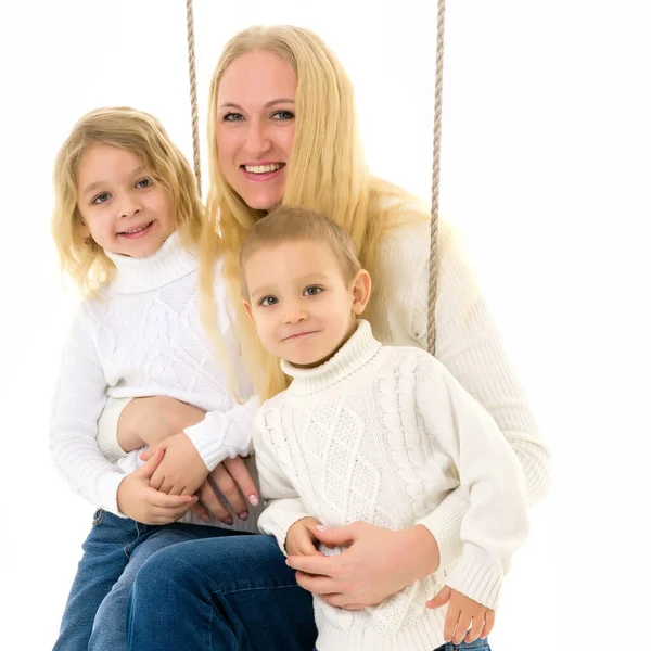 Glückliche Familie aus Mutter und zwei Kindern, die zusammen auf dem Seil sitzen — Stockfoto