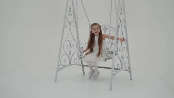 Happy little girl schoolgirl swinging on a swing. — Stock Video