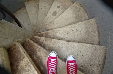 Red sneakers on spiral staircase when going downhill clipart