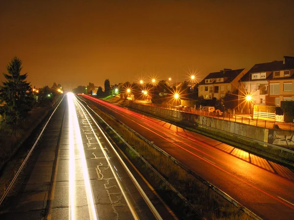 夜间高速公路与住宅和尾灯和白色光斑灯 — 图库照片