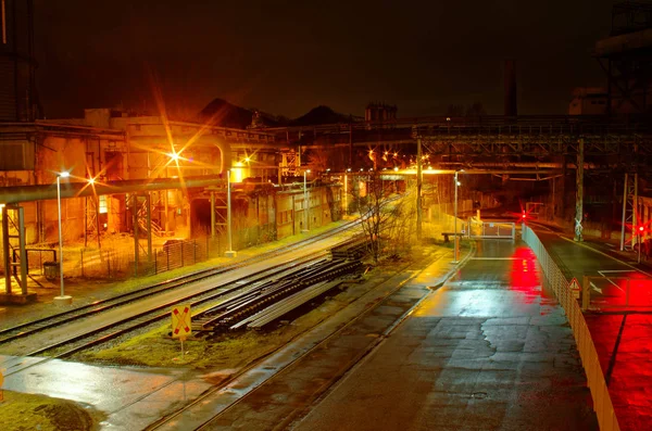 Industrial rail yard shunting station at night with many lights and wagons on a siding in an industrial plant