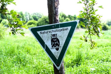 Uyarı işareti doğa rezerv içinde - bir çanta çöp ile asılı idi tabiatı atık