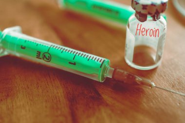 Tahta bir masanın üzerinde kanüllü şırınga ve ilaç.