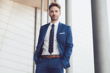 Yakışıklı erkek model mavi bir takım elbise poz.