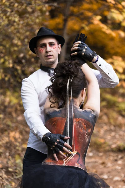 Homem tocando violino que pintado na pele das costas da mulher — Fotografia de Stock