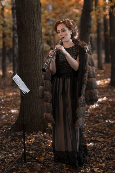 Jeune femme attrayante jouant hautbois dans le parc d'automne — Photo