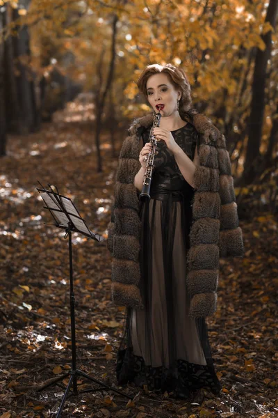 秋の公園でクラリネットを演奏若い魅力的な女性 — ストック写真