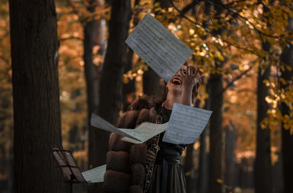 Joven atractiva mujer sosteniendo ébano lanzando las hojas musicales — Foto de Stock