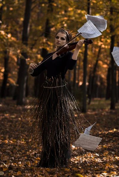 Jovem mulher atraente tocando violino sobre as notas voadoras e queda de fundo do parque — Fotografia de Stock
