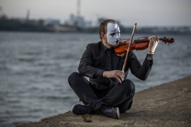 Riverside ve oyun keman üzerinde açık havada oturma Mim