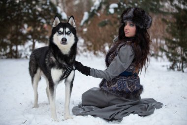 Güzel kız kış Park husky ile kar üzerinde oturarak 