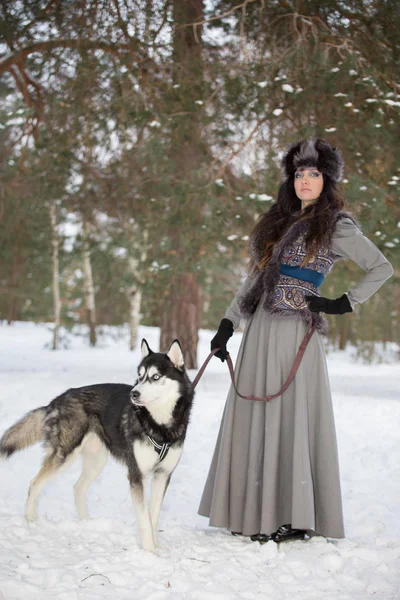 Portret van mooie vrouw boven de sneeuwt park achtergrond met wolf hond staan — Stockfoto