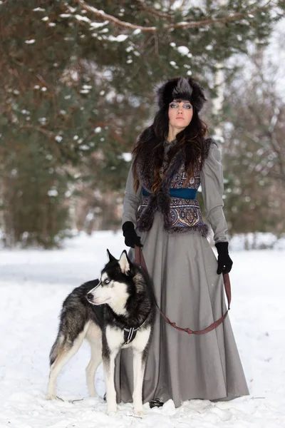 Портрет красивої жінки, що стоїть з хаскі собакою в сніжному парку — стокове фото