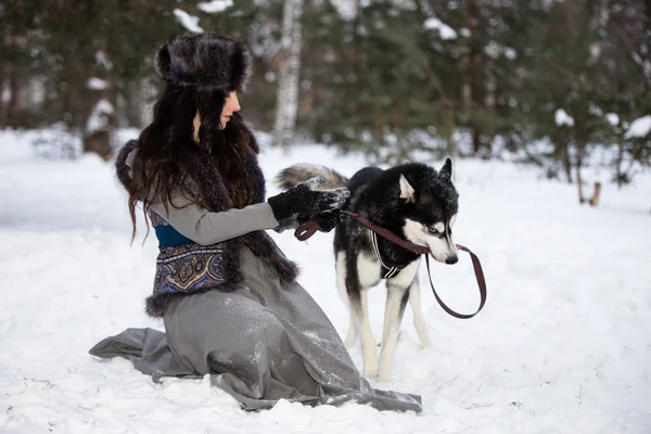 Vonzó lány játszik husky kutya Park snow — Stock Fotó