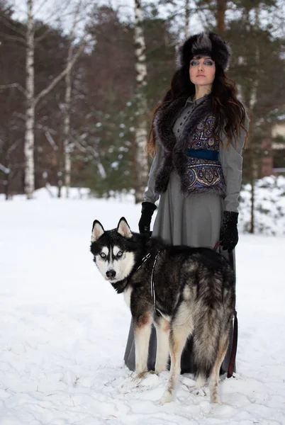 年轻漂亮的女人站在雪园的赫斯基狗的肖像 — 图库照片