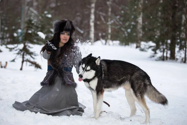 Menina atraente jogando neve no cão husky brincalhão — Fotografia de Stock