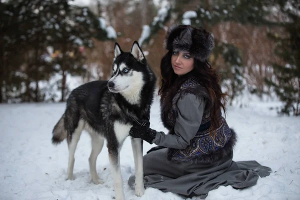 Menina bonita sentada na neve com cão husky no parque de inverno — Fotografia de Stock