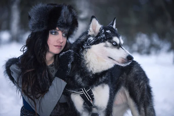 Jovem mulher com cão husky olhando para o lado no parque de neve — Fotografia de Stock