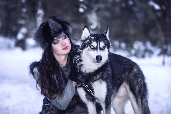 Atrakcyjna, młoda kobieta, patrząc na psa husky w śnieg park — Zdjęcie stockowe