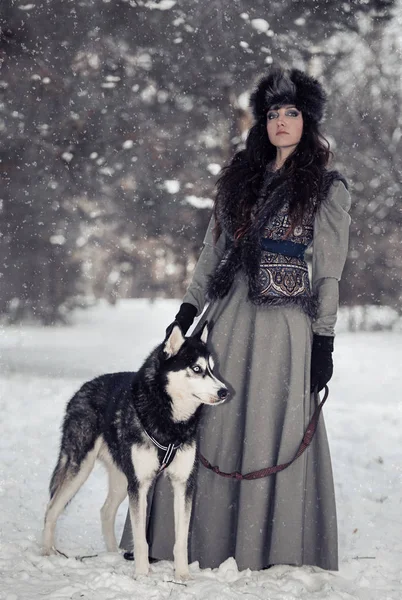 公園の雪でハスキーに立っている美しい若い女性の肖像画 — ストック写真
