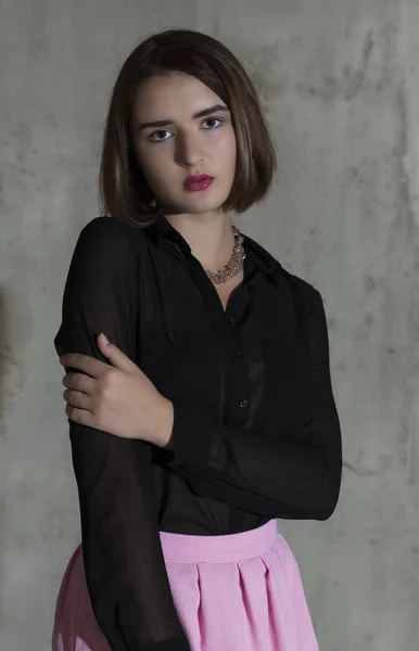 Молодая женщина, стоящая в черной рубашке с длинными рукавами и розовой юбке — стоковое фото