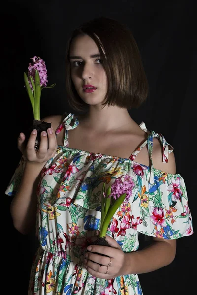 Половина привлекательной девушки, держащей два свежих гиацинтовых цветка луковицами и смотрящей в камеру — стоковое фото