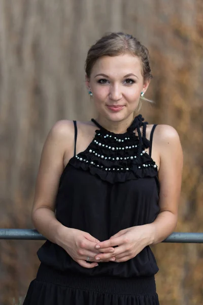 Mooi blond meisje dragen zwarte jurk staande over de bruin muur — Stockfoto