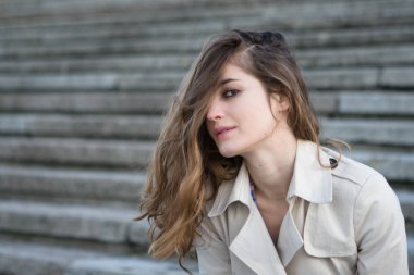 Beton merdiven üzerinde bej ceketi giyen genç güzel kadın portresi