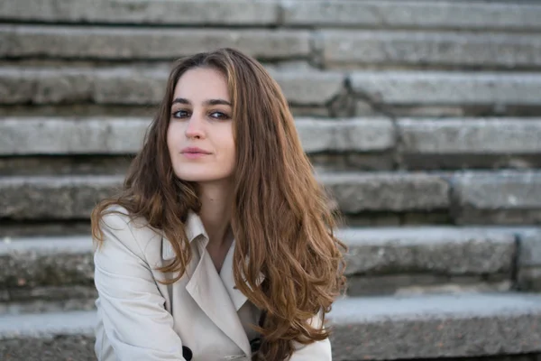 Retrato de jovem mulher bonita vestindo jaqueta bege sobre a escada de concreto — Fotografia de Stock