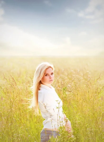 Mooie jongedame permanent in veld in zonnige dag — Stockfoto